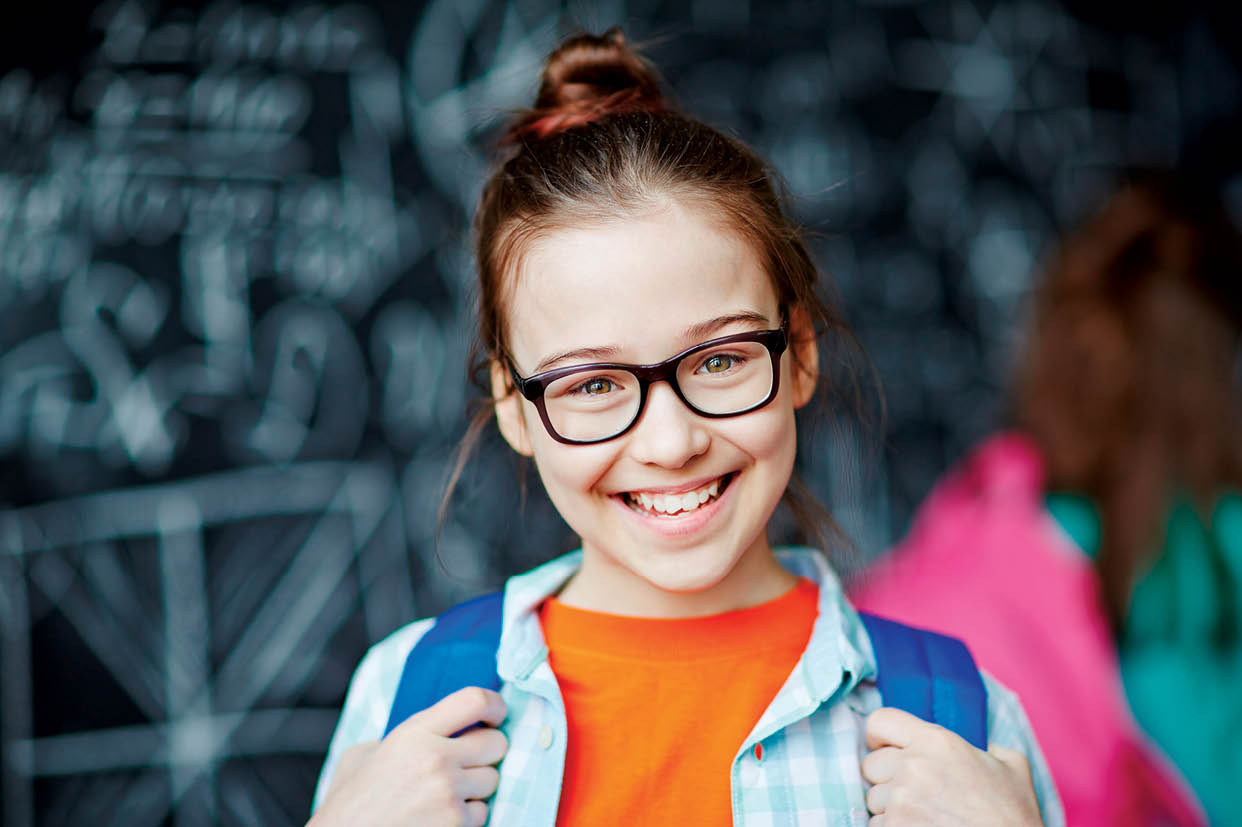 Happy little girl wearing glasses looking at camera