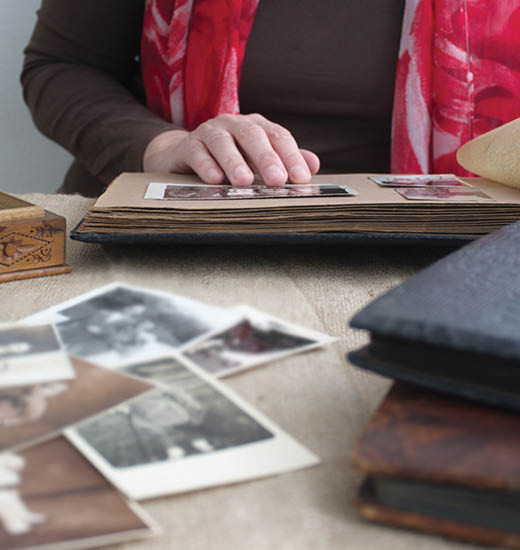 Midsection of woman holding old retro photo album with vintage monochrome photographs in sepia color