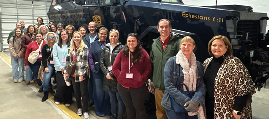 A group of people pose in front of a large black truck. AI generated content
