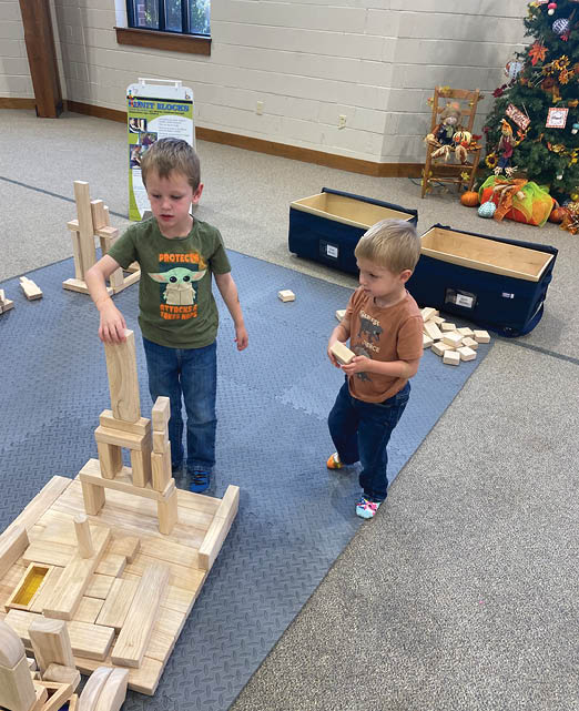 Two children are playing with wooden blocks on a carpeted floor. AI generated content