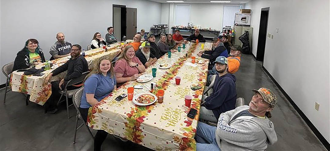A group of people are sitting around a table with a tablecloth and plates of food. AI generated content