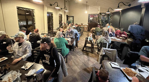 A group of people are sitting around a table in a restaurant, enjoying a meal together. AI generated content