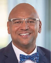 A man wearing a blue suit and a bow tie is smiling for the camera. AI generated content