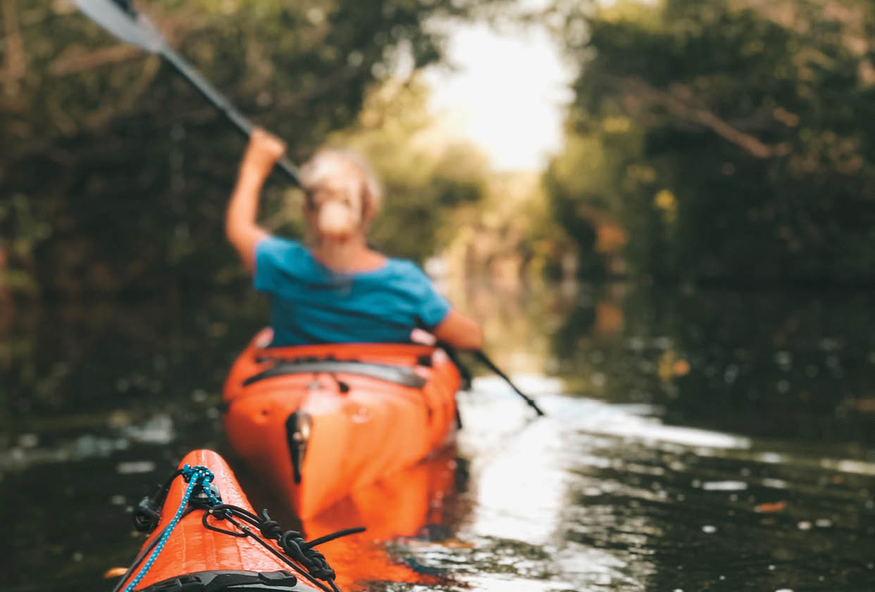 A person is paddling a red kayak in a river. AI generated content