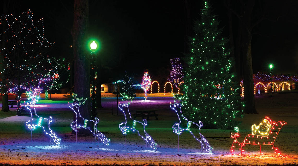 Festive town square Christmas display featuring a lighted Santa in sleigh and four purple reindeer