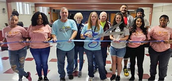 A group of people are standing in a room, holding a blue ribbon. AI generated content