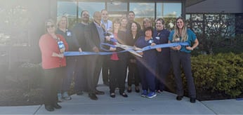 A group of people are standing in front of a building, holding a ribbon. AI generated content