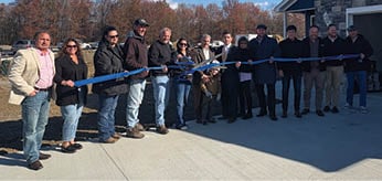 A group of people are standing in front of a house, holding a blue ribbon. AI generated content