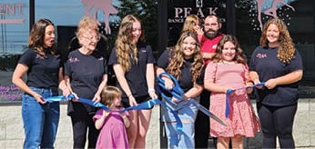 A group of people, including children, are standing in front of a dance studio. They are holding ribbons and posing for a picture. AI generated content