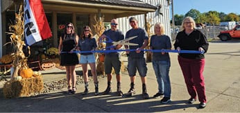 Four people are standing in front of a building, holding a ribbon. They are posing for a photo. AI generated content