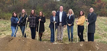A group of people are standing in a field, holding shovels and posing for a picture. AI generated content