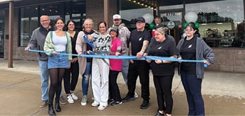 A group of people are standing in front of a building, holding a ribbon. AI generated content