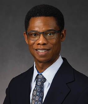 A man wearing a suit and tie is smiling for the camera. AI generated content