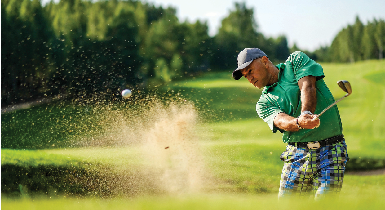 Golfer hits ball from a bunker with golf club. Golfer playing golf