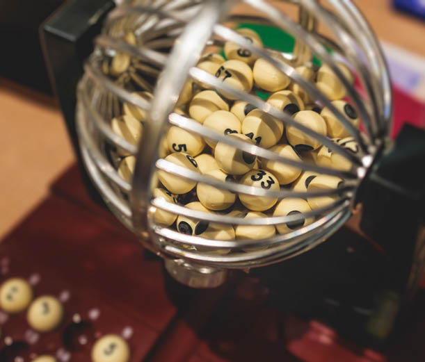 Process of prize drawings, extracting a winning numbers of lottery machine, raffle drum with a bingo balls, bingo machine and winning tickets on event with a host, hands on a lottery machine