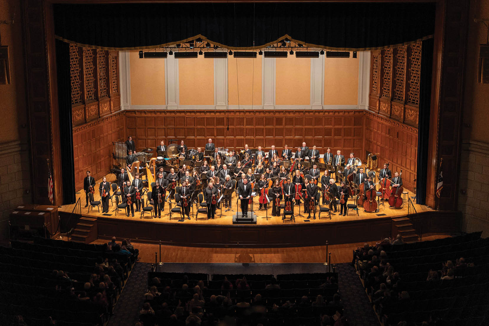 A large group of people are sitting in the audience of a concert. Description generated by AI