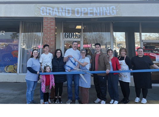 A group of people are standing in front of a blue ribbon. Description generated by AI